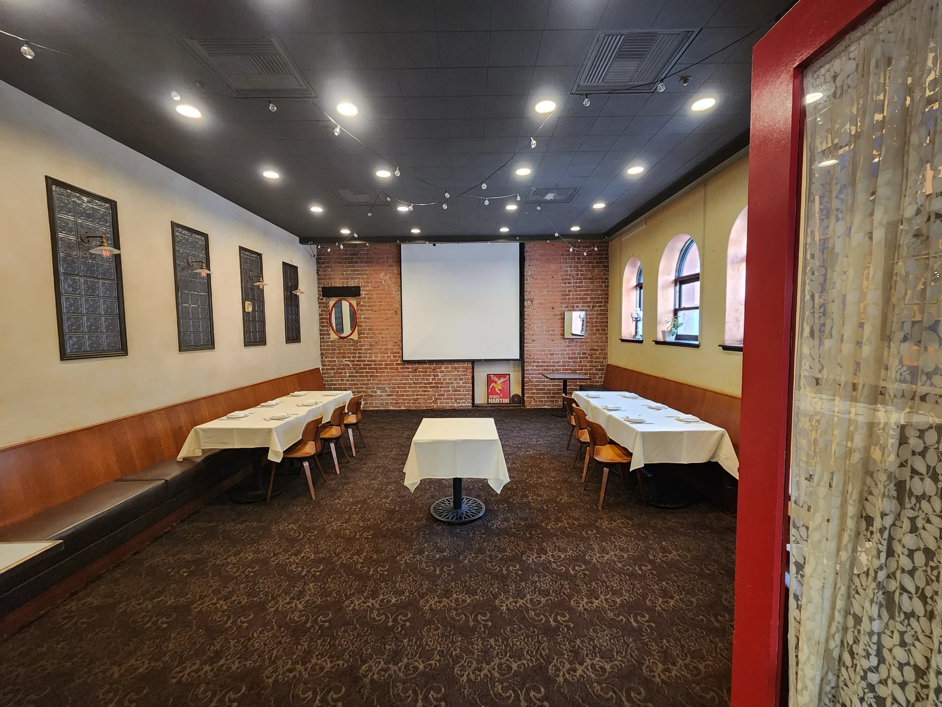 A restaurant with a large screen and tables.