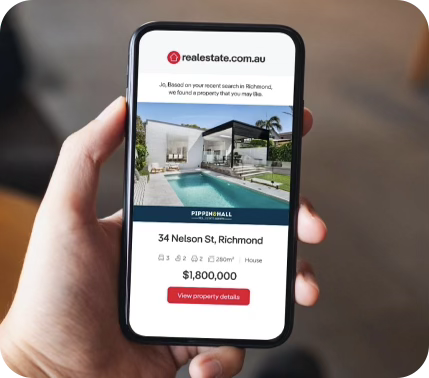 Hand holding a smartphone displaying a real estate listing app.