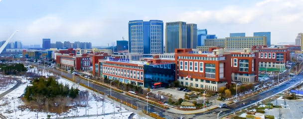 Aerial view of a modern urban area with multi-story commercial and office buildings surrounded by snowy ground and roads.