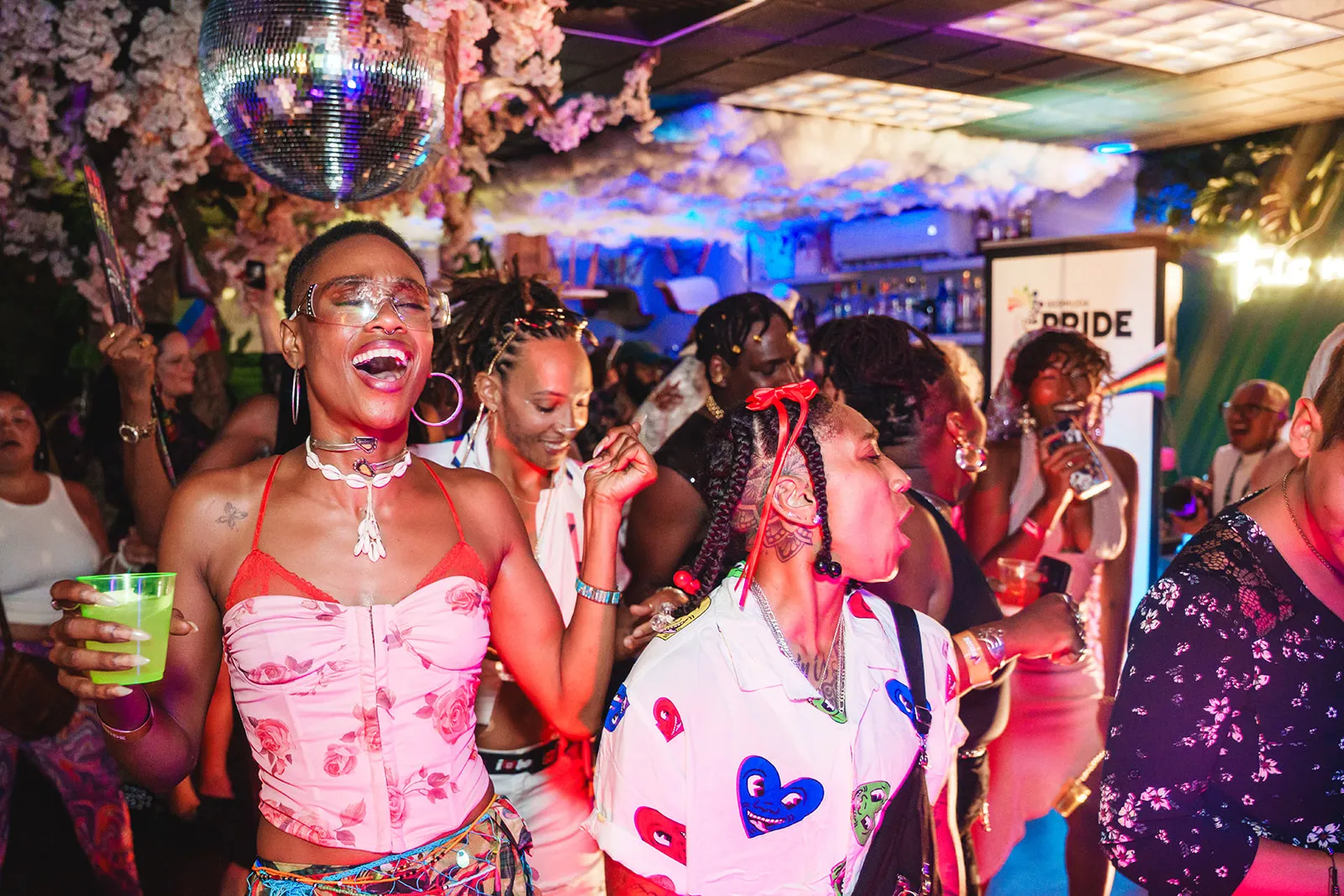 People dancing and enjoying a lively party under a disco ball with colorful lights and decorations.