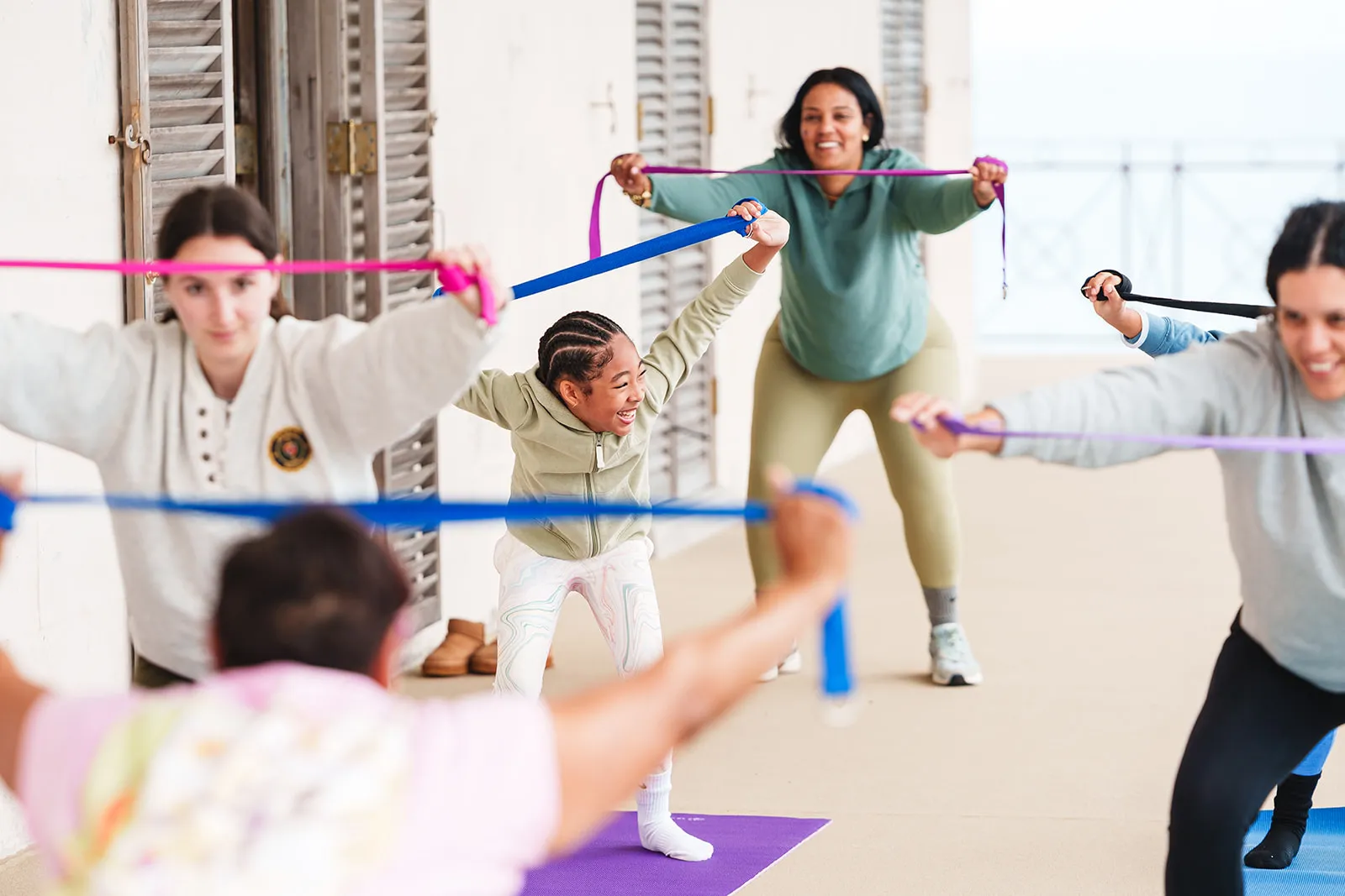 Group of diverse people stretching with resistance bands in a bright exercise room.