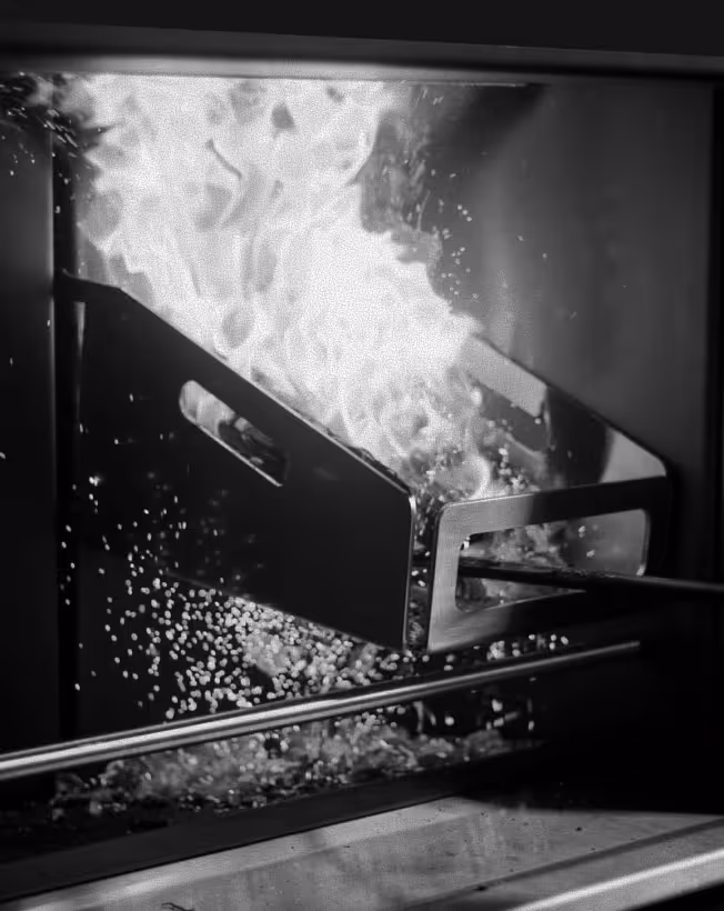 Close-up of popcorn popping inside an oven with flames visible.