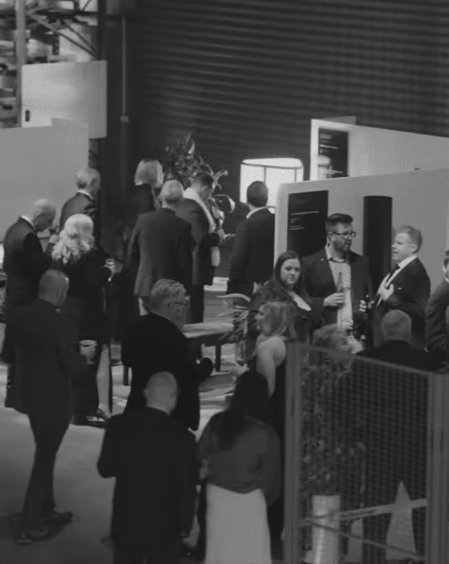 Group of people dressed in business attire networking and socialising indoors at an event or conference.