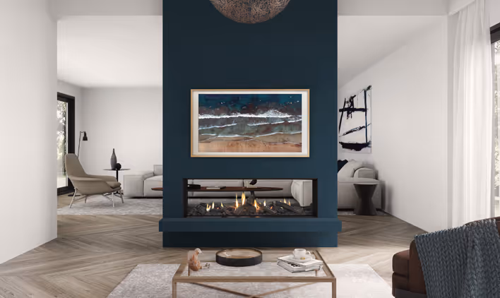 Modern gas fireplace with realistic burning logs set in a light-coloured wall next to a wooden side table with books.