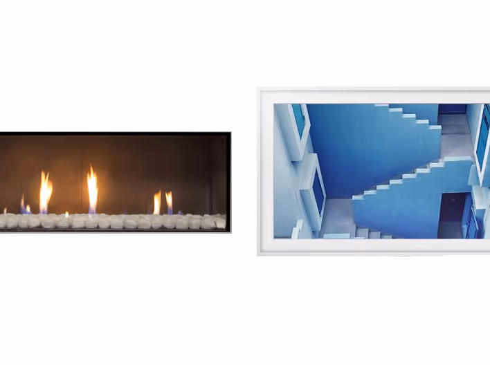 Modern gas fireplace with realistic burning logs set in a light-coloured wall next to a wooden side table with books.