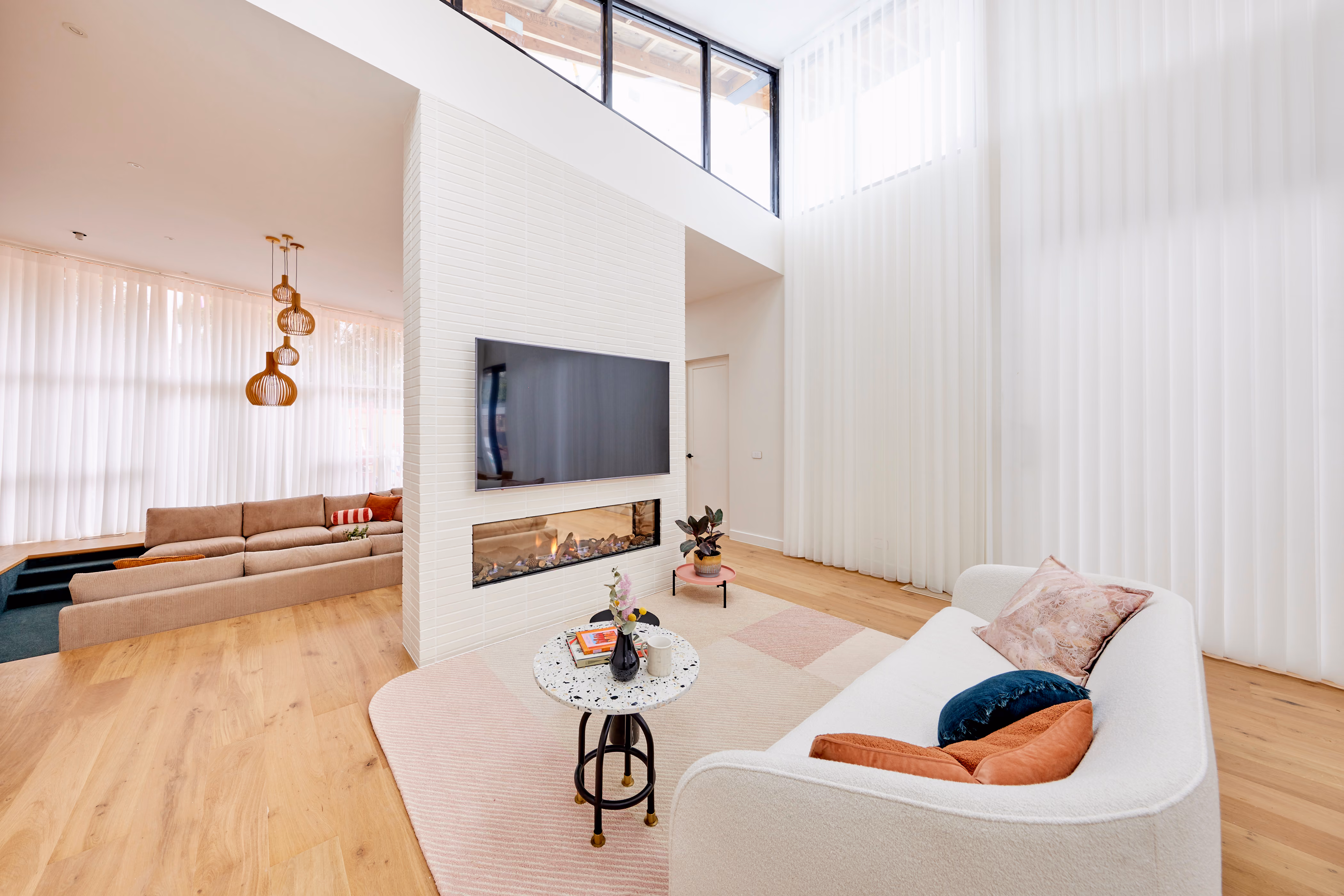 Modern gas fireplace with realistic burning logs set in a light-coloured wall next to a wooden side table with books.