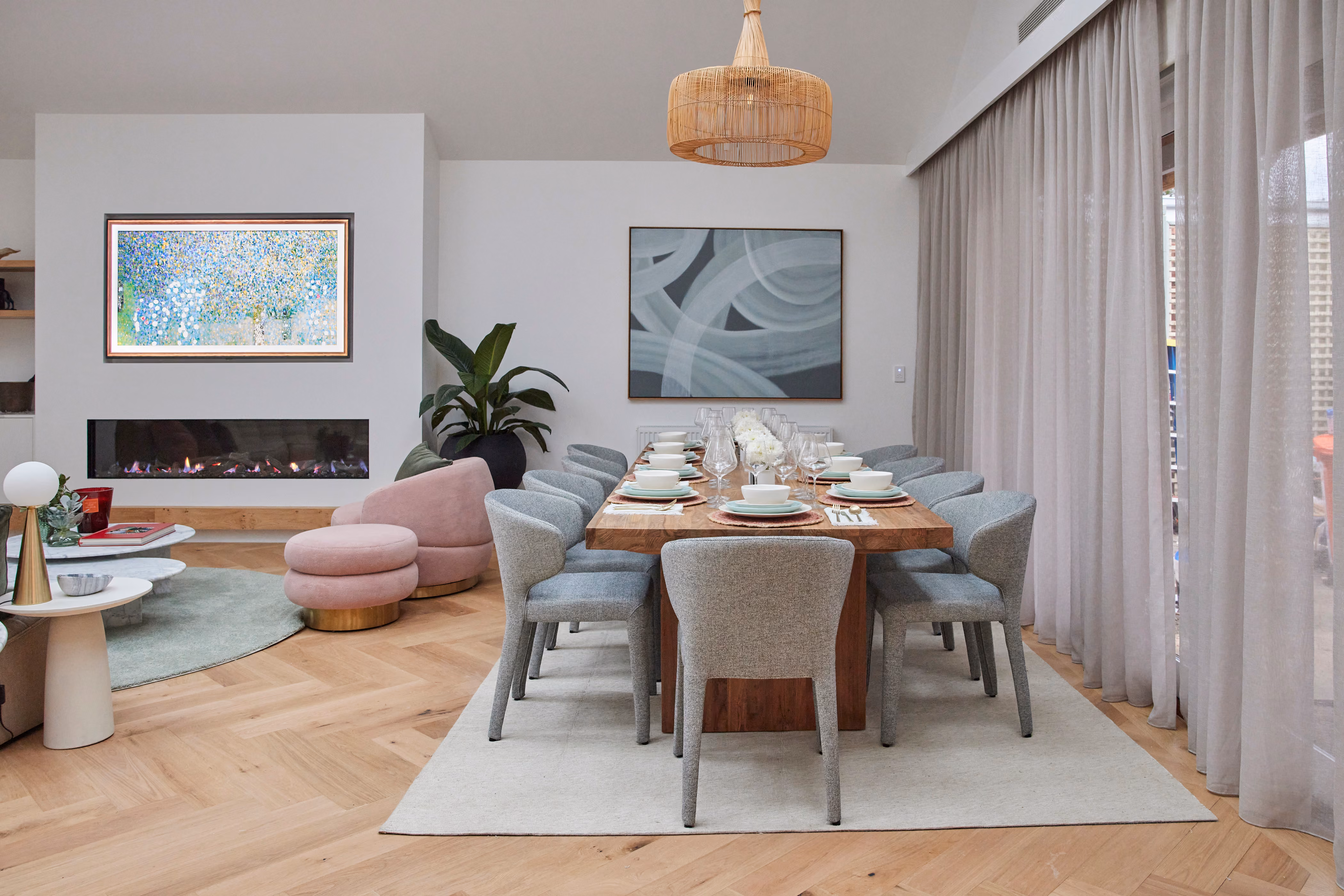 Modern gas fireplace with realistic burning logs set in a light-coloured wall next to a wooden side table with books.