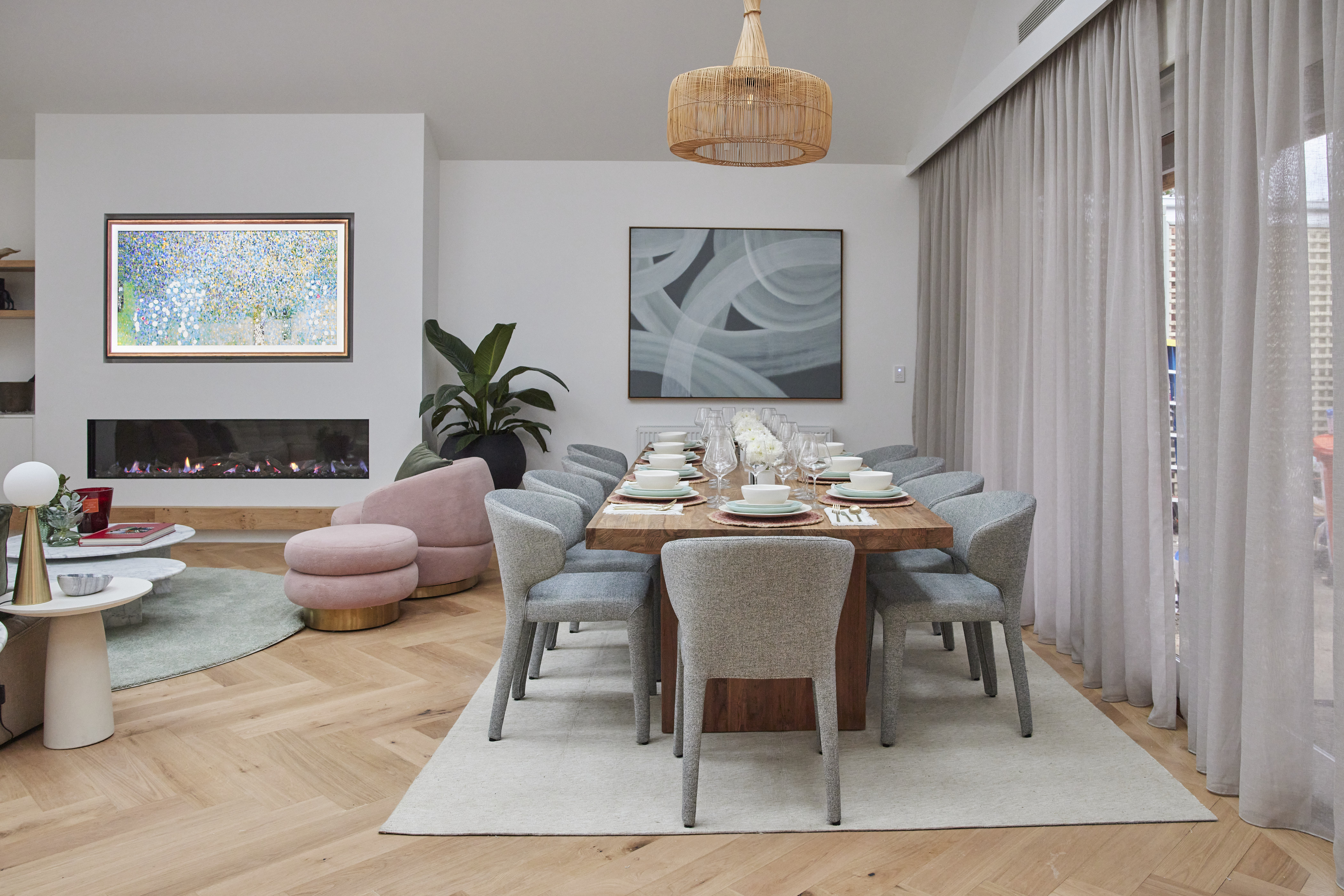 Modern gas fireplace with realistic burning logs set in a light-coloured wall next to a wooden side table with books.