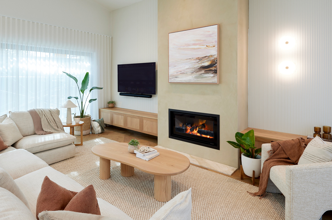 Modern gas fireplace with realistic burning logs set in a light-coloured wall next to a wooden side table with books.