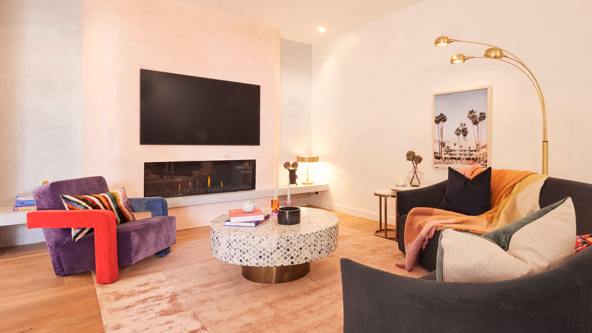 Modern gas fireplace with realistic burning logs set in a light-coloured wall next to a wooden side table with books.
