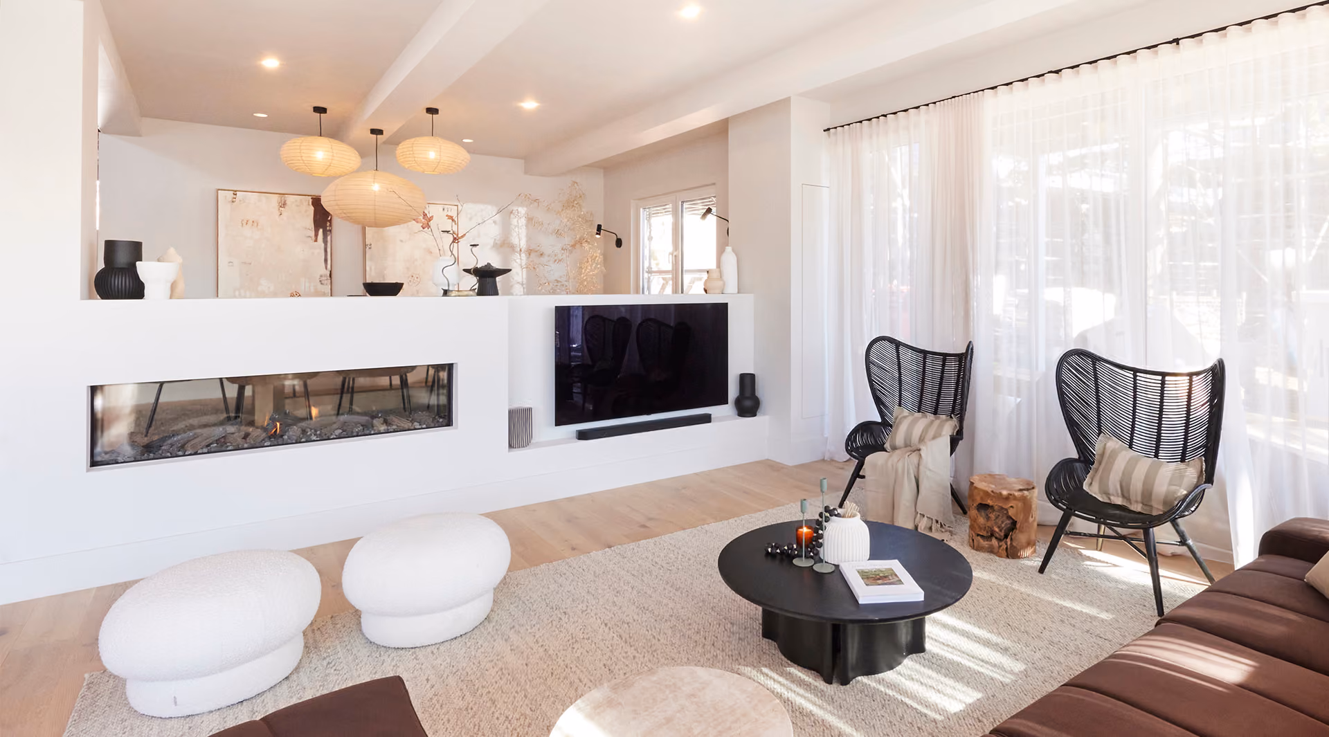 Modern gas fireplace with realistic burning logs set in a light-coloured wall next to a wooden side table with books.