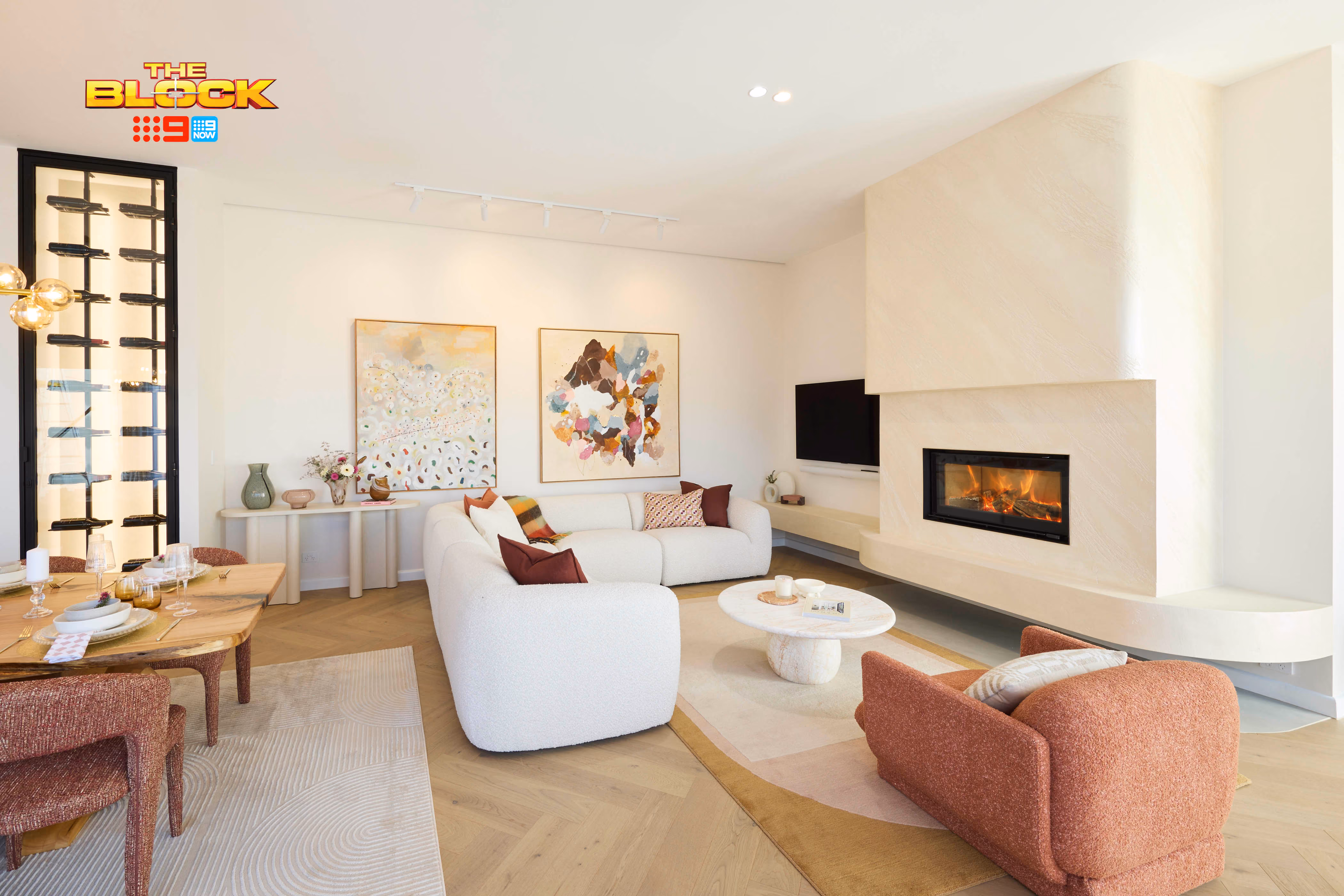 Modern gas fireplace with realistic burning logs set in a light-coloured wall next to a wooden side table with books.