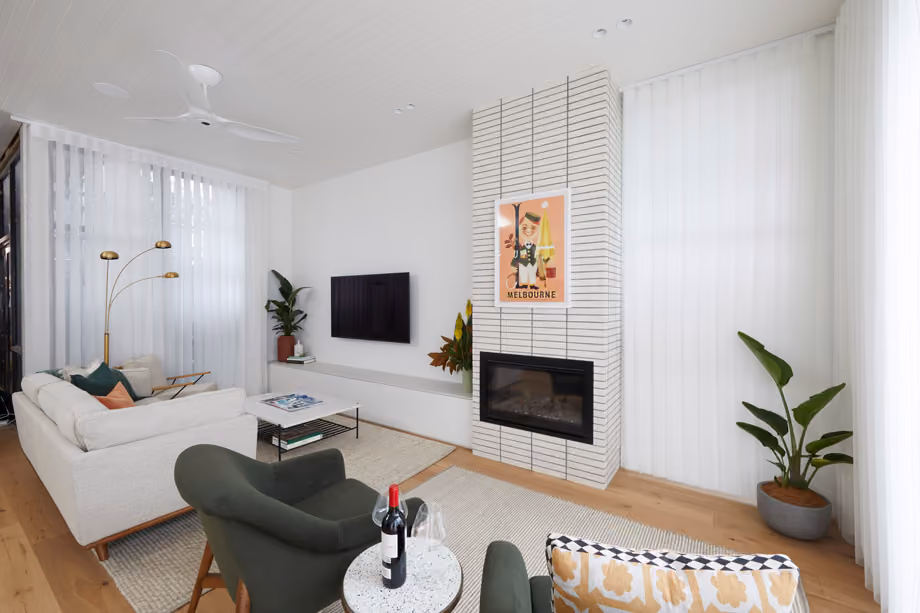 Modern gas fireplace with realistic burning logs set in a light-coloured wall next to a wooden side table with books.