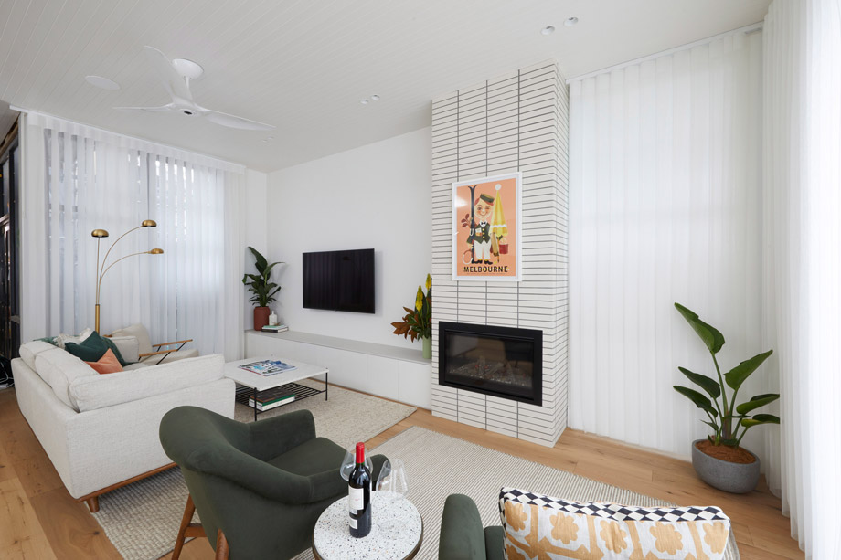 Modern gas fireplace with realistic burning logs set in a light-coloured wall next to a wooden side table with books.