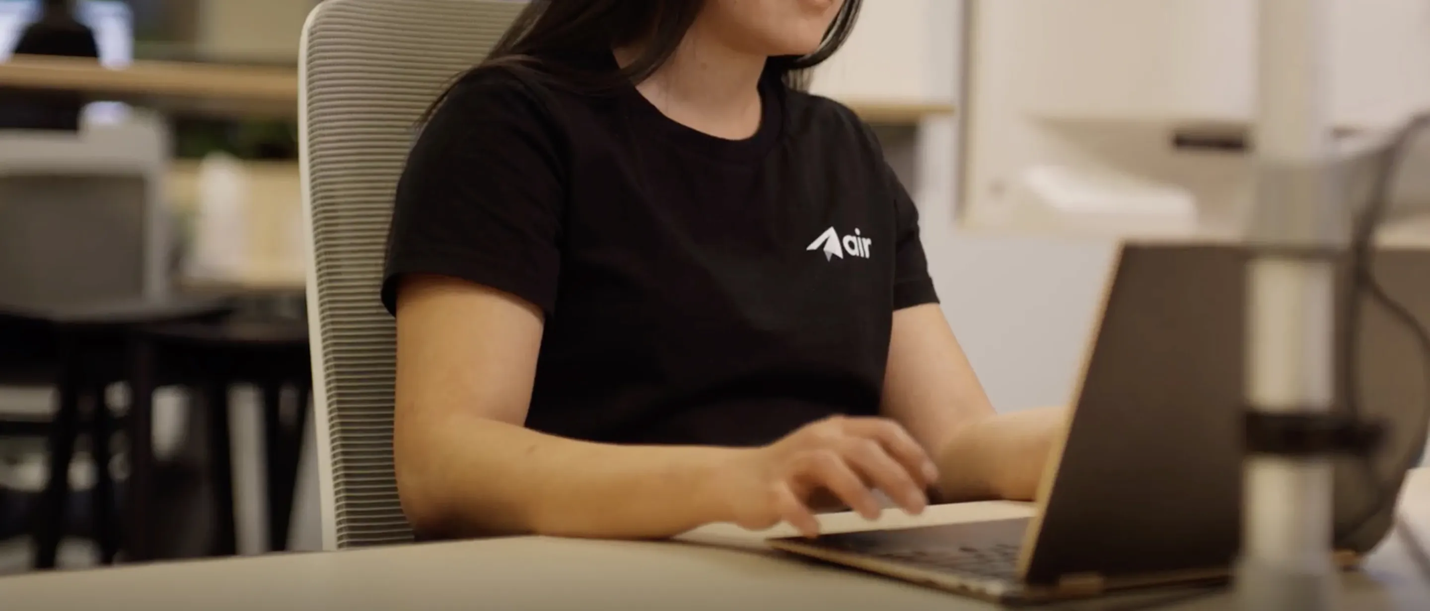 A woman sitting at a desk using a laptop computer.