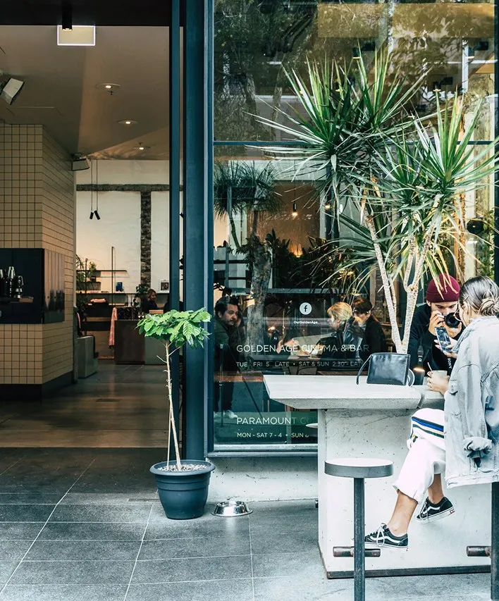 A woman sitting at a table using a cell phone.