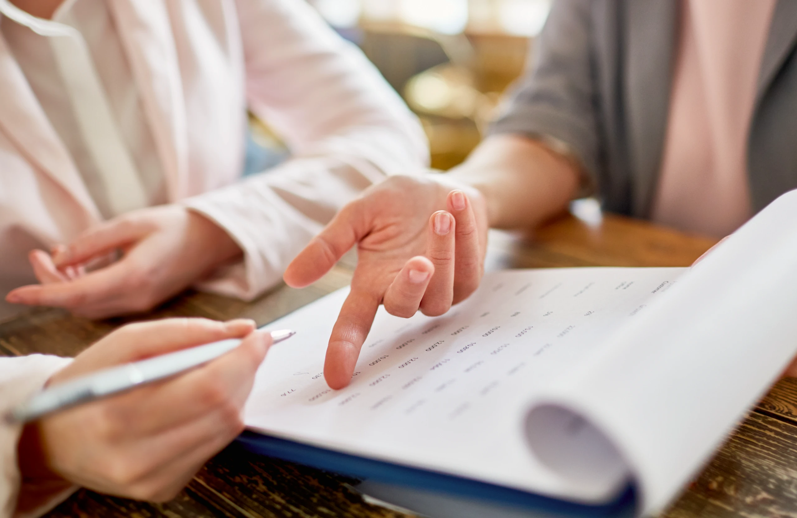 Two people reviewing a document with one person pointing at the paper and the other holding a pen.