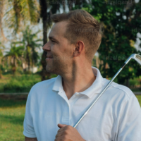 Man in white polo shirt holding a golf club outdoors with trees in the background.