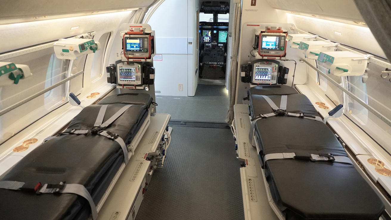 Interior of an air ambulance with two stretcher beds equipped with medical monitors and safety straps.