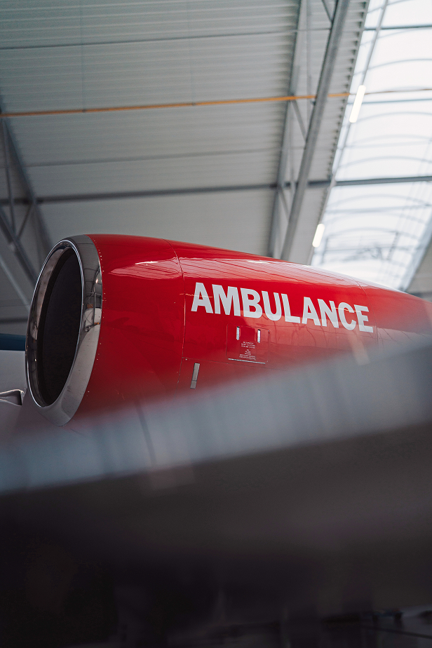 Close-up of a red airplane engine with the word AMBULANCE written on it, inside a hangar.
