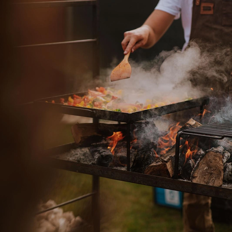 Vlees grillen op open vuur met intense vlammen - authentieke BBQ catering