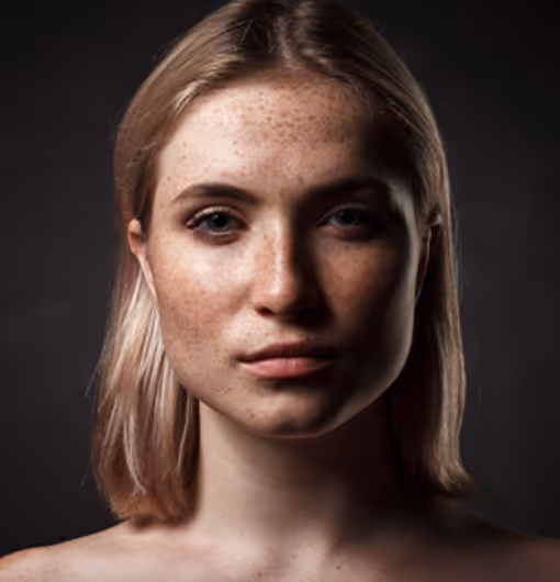 Close-up portrait of a young woman with blonde hair and freckles against a dark background.