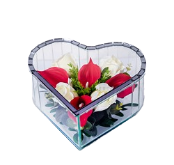 Heart-shaped glass container holding red and white flowers with green leaves.