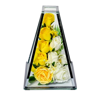 Clear glass pyramid vase containing yellow and white roses with green leaves inside.