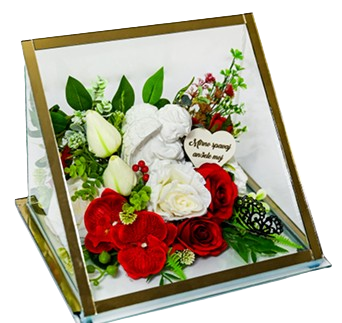Memorial plaque with an angel figure surrounded by red and white flowers and green leaves inside a transparent case.