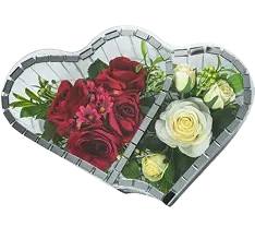 Heart-shaped arrangement featuring red and white roses surrounded by green foliage and small pink flowers.
