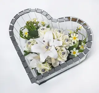 Glass shadow box containing a floral arrangement with red roses, white lilies, and green foliage.
