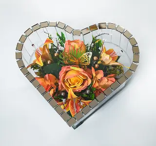 Glass shadow box containing a floral arrangement with red roses, white lilies, and green foliage.