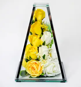 Glass pyramid vase containing purple orchids, white roses, green fern leaves, and a decorative silver butterfly.