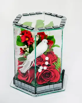 Hexagonal glass vase with blue and white artificial flowers and decorative pearl accents.