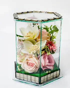 White decorative bird perched inside a hexagonal glass case adorned with red roses, green leaves, and white berries.