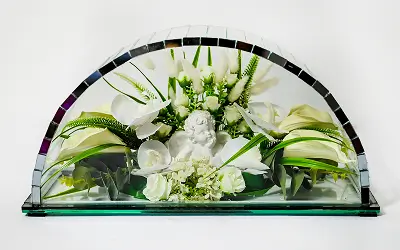 Decorative glass dome with white flowers and a small angel figurine inside.