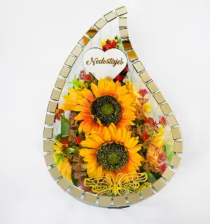 Decorative teardrop-shaped glass frame with two large sunflowers, small red flowers, and yellow butterfly inside, featuring a card with the word 'Nedostajes'.