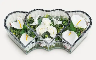 Decorative mirrored heart-shaped frame holding blue orchids, white roses, and green foliage.