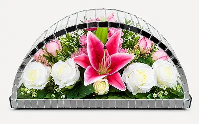 White angel figurine surrounded by white roses and greenery inside a dome-shaped glass enclosure with a gold and green border.