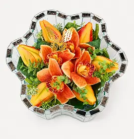Flower arrangement with red roses and white calla lilies in a scalloped glass vase.