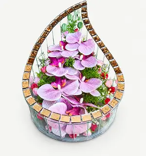 Teardrop-shaped mirrored vase holding red roses, white ribbons, greenery, and a heart-shaped tag with a message.