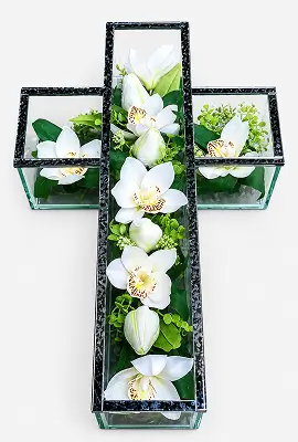 Glass cross filled with pink roses, white flowers, and green foliage on a white background.