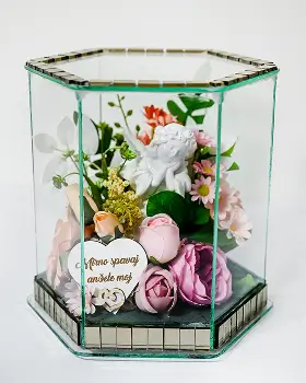 Rectangular glass and gold-trimmed display box containing an arrangement of white, cream, and peach artificial flowers with green foliage and a decorative silver butterfly.