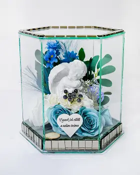 Glass shadow box containing a floral arrangement with red roses, white lilies, and green foliage.
