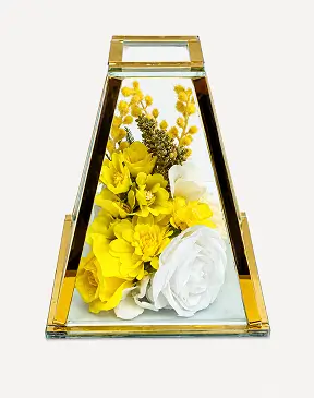 Glass terrarium with a metal frame displaying pink and white artificial flowers inside.