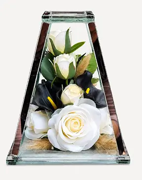 Triangular glass case containing red roses, green foliage, and a white dove figurine.
