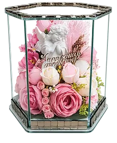 Rectangular glass box with gold edges containing a floral arrangement of white, cream, and peach flowers with green leaves.