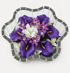 Top view of a floral arrangement with white roses and green foliage inside a star-shaped glass vase.