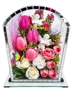 Glass pyramid display containing a white figurine surrounded by cream roses and green leaves.