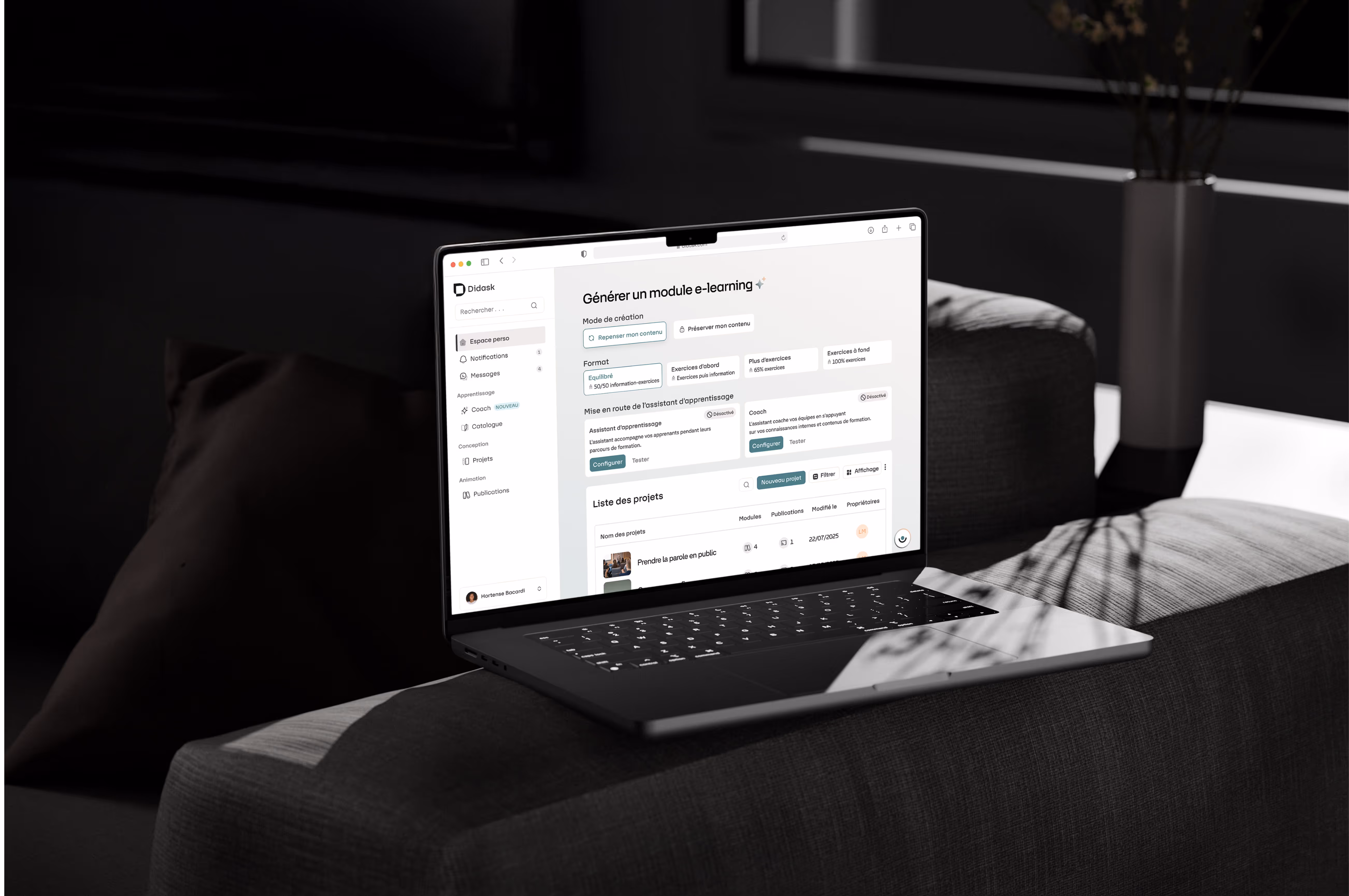 Ordinateur portable ouvert affichant la plateforme Didask avec un module e-learning sur un canapé gris dans une pièce sombre.